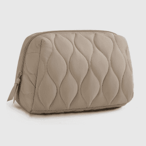 Home A closed khaki pink wave quilted cosmetic bag with a zipper standing upright on a white background.