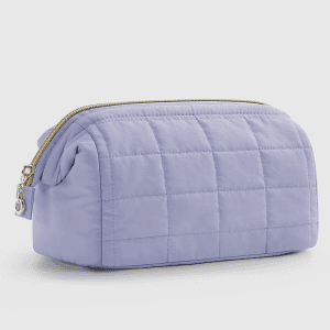Home A light purple quilted cosmetic bag with a gold zipper resting on a white surface.