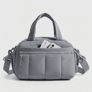 Home A beige quilted puffer travel bag with nylon handles and a side zipper pocket revealing a pair of white sneakers inside