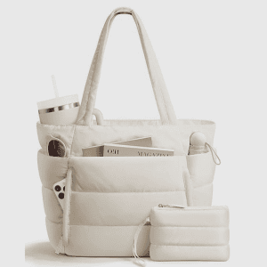 Home A beige quilted puffer tote bag filled with a magazine a 40 oz tumbler sunglasses and a phone with a matching small pouch in front.