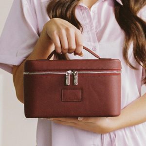 Woman holding leather makeup case by the top handle