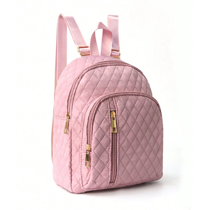 07 A pink quilted mini backpack with a front zip pocket and adjustable shoulder straps standing on a white surface.