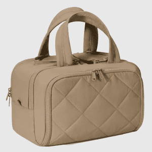 A closed khaki quilted travel bag with a top handle and a front zipper pocket standing on a white background.